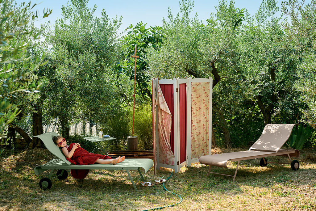 Une femme est allongée sur une chaise longue dans une zone herbeuse.