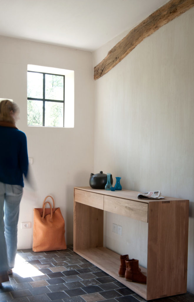 Une femme marchant dans une pièce avec un banc en bois.