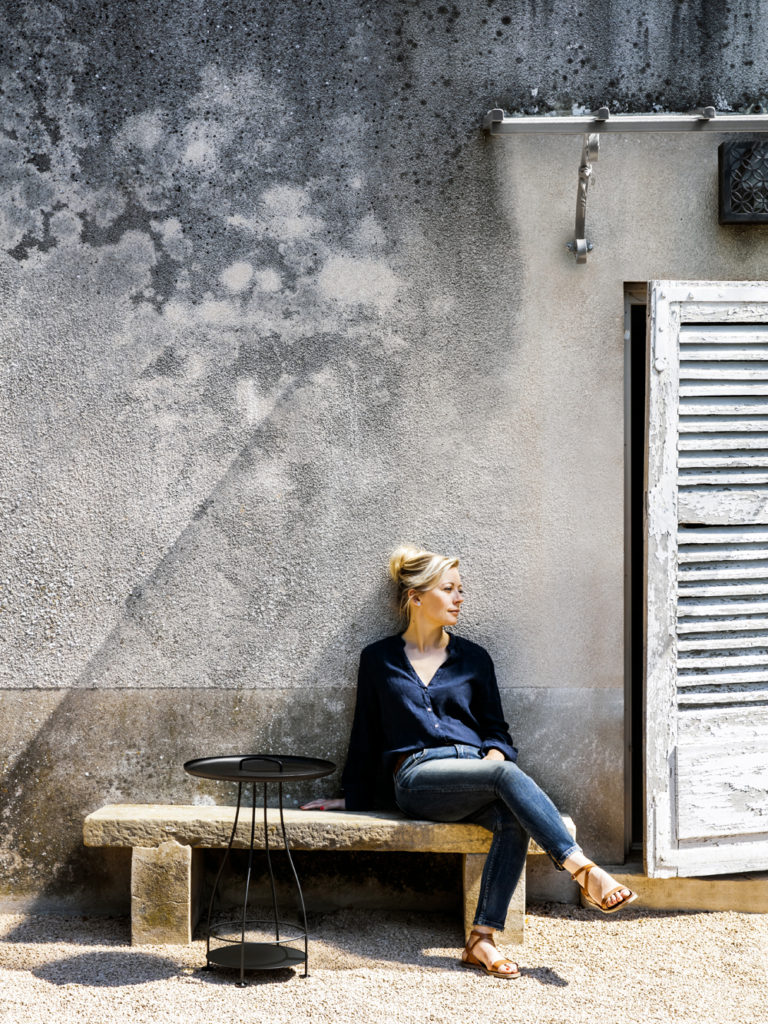 Une femme assise sur un banc devant un immeuble.