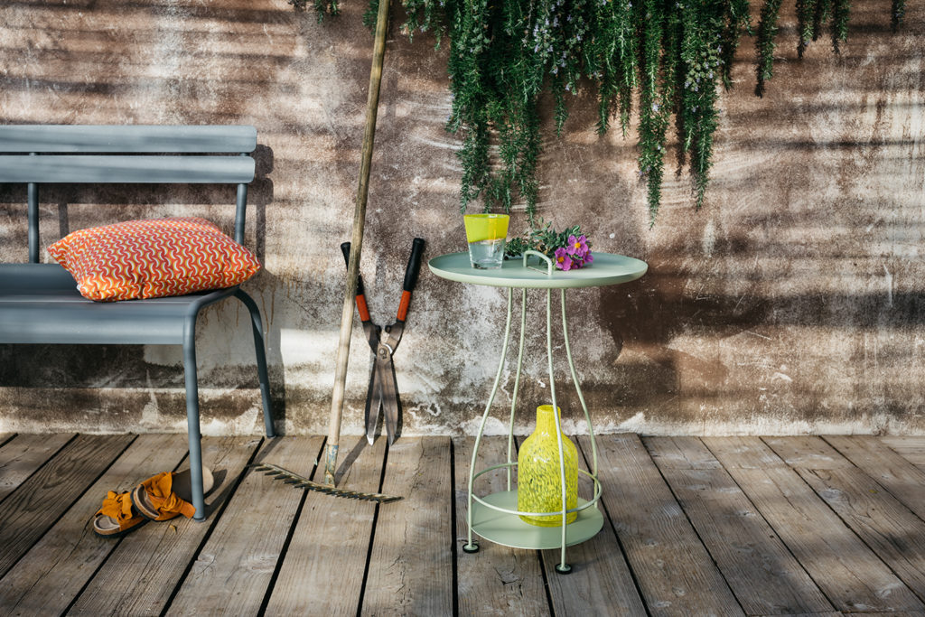 Une table avec une bouteille de vin dessus à côté d'un banc.