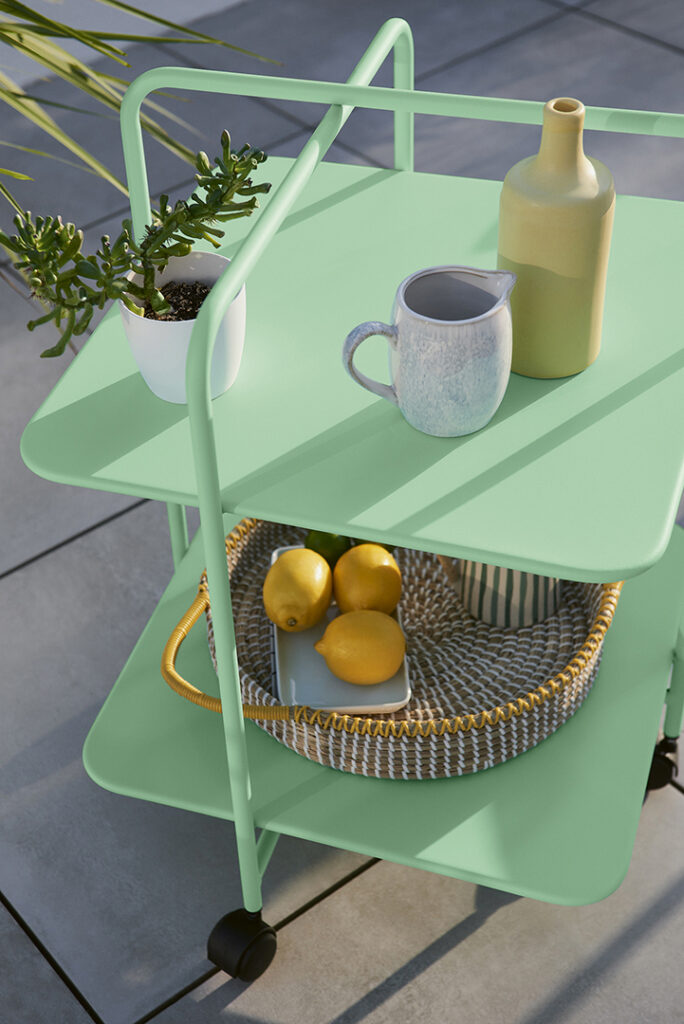 Une charrette verte avec des citrons se trouve à côté du Guéridon Alfred.