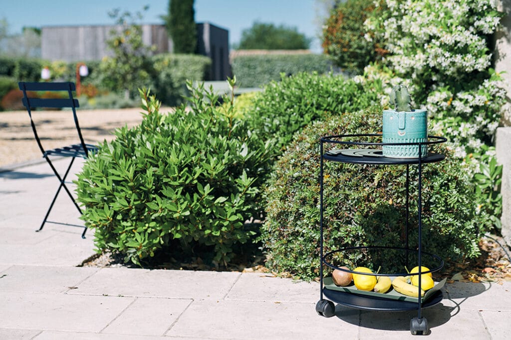 Un chariot Guéridon Guinguette sur roulettes noir avec un bouquet de fruits dessus.