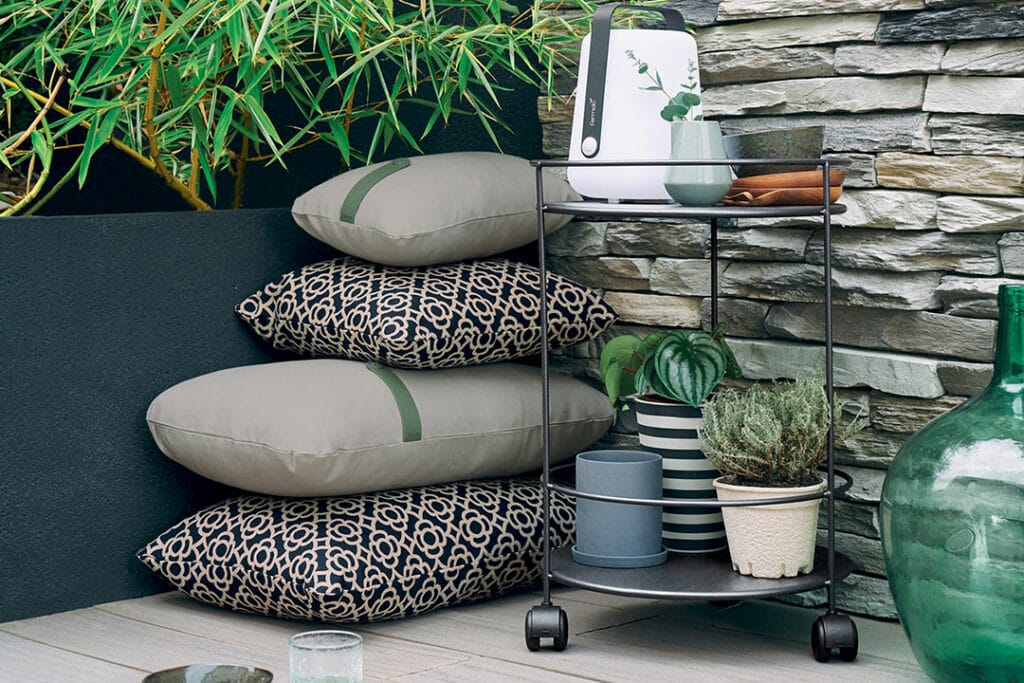 Une pile de Guéridon Guinguette sur roulettes sur un patio en pierre.