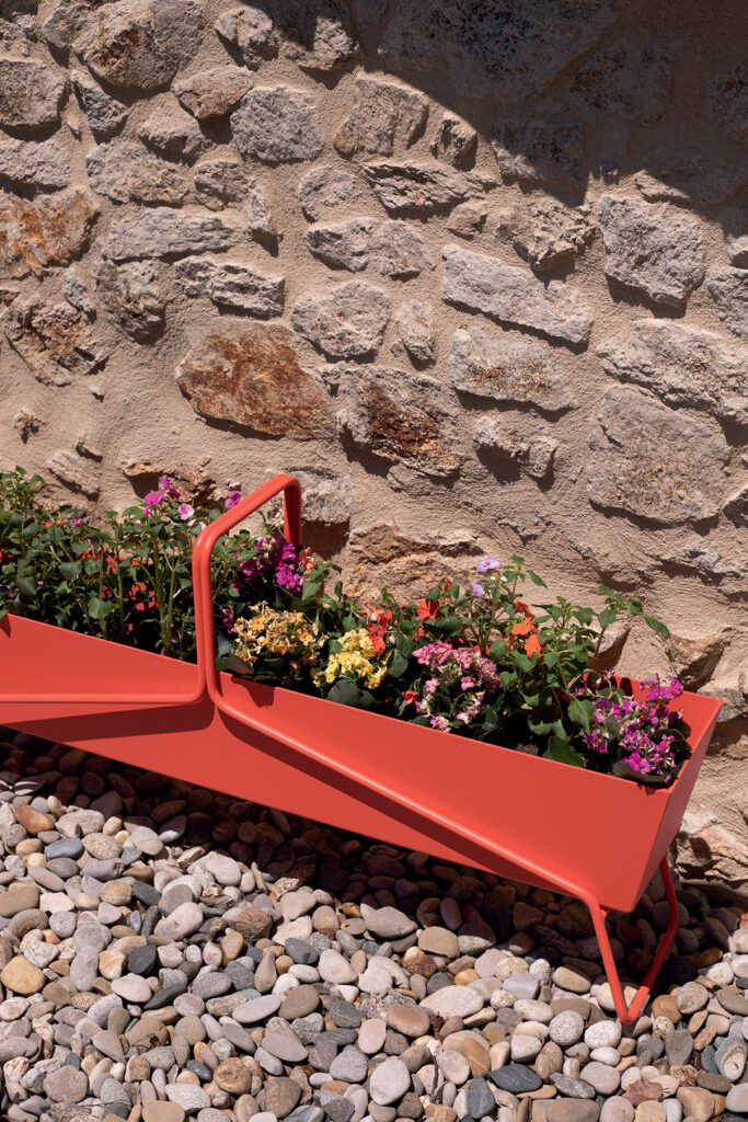 Une jardinière corbeille longue en métal à décor de fleurs.