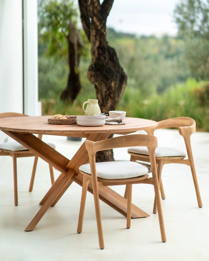 Une table à manger et des chaises Bok avec un coussin Coussin sur les sièges en bois, sur fond d'arbre.