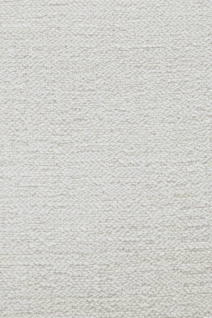 Un gros plan d'un coussin en tissu tissé blanc.