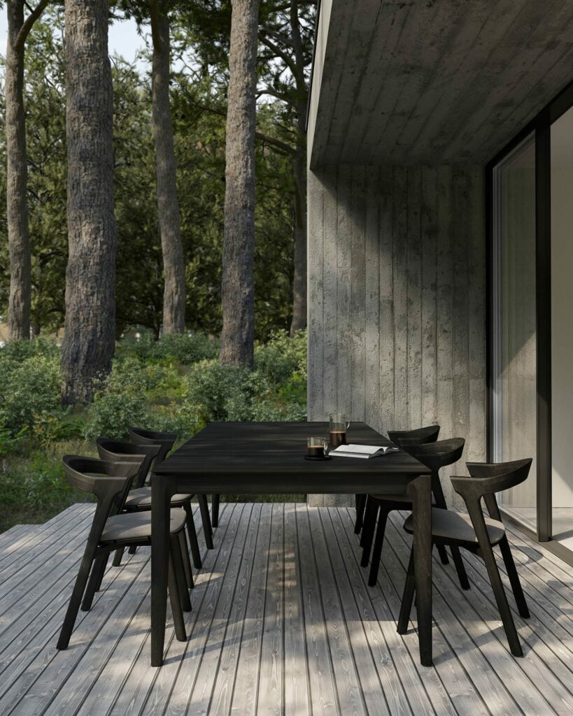 Une terrasse en bois avec table et chaises dans le bois, agrémentée de l'ajout cosy de coussins "Coussin pour chaise de jardin Bok".