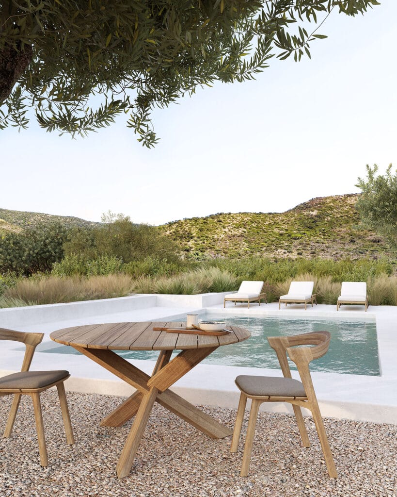 Une table et des chaises en bois au bord d'une piscine, avec les confortables coussins Coussin pour chaise de jardin Bok.