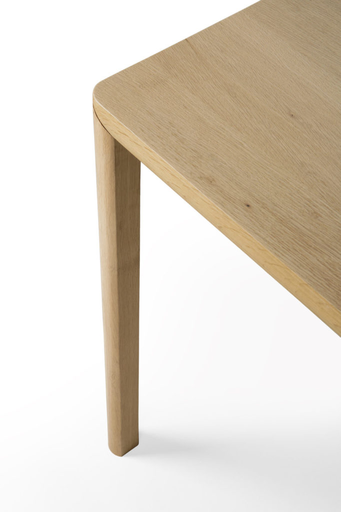 Une table en chêne naturel, avec un plateau et des pieds en bois.