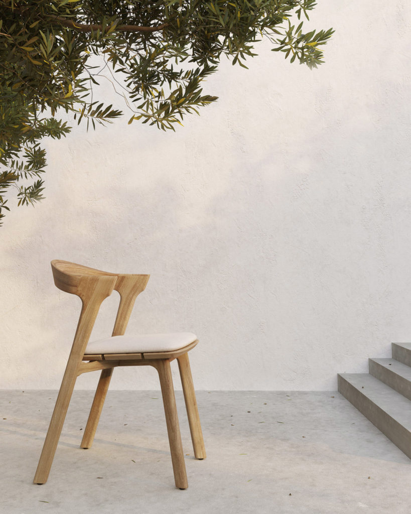 Un Coussin de chaise de jardin Bok repose sur un sol en béton à côté d'un arbre.