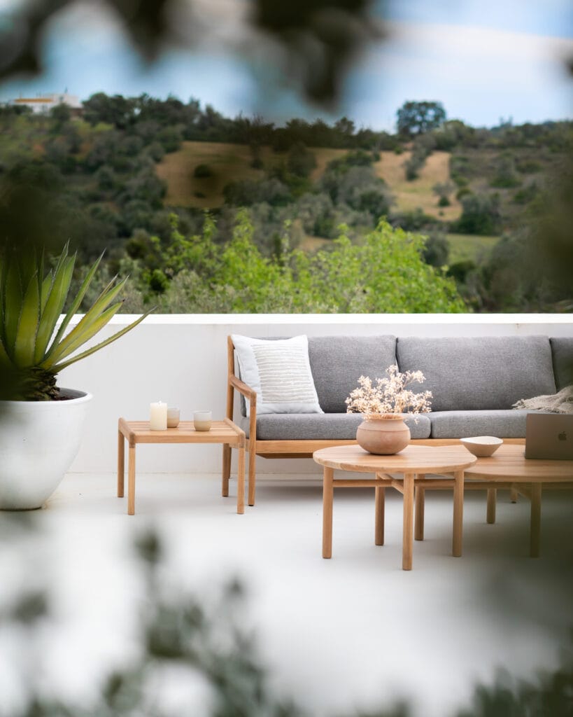 Une terrasse en bois avec un canapé gris et une plante en pot, avec la Table basse de jardin Quatro.