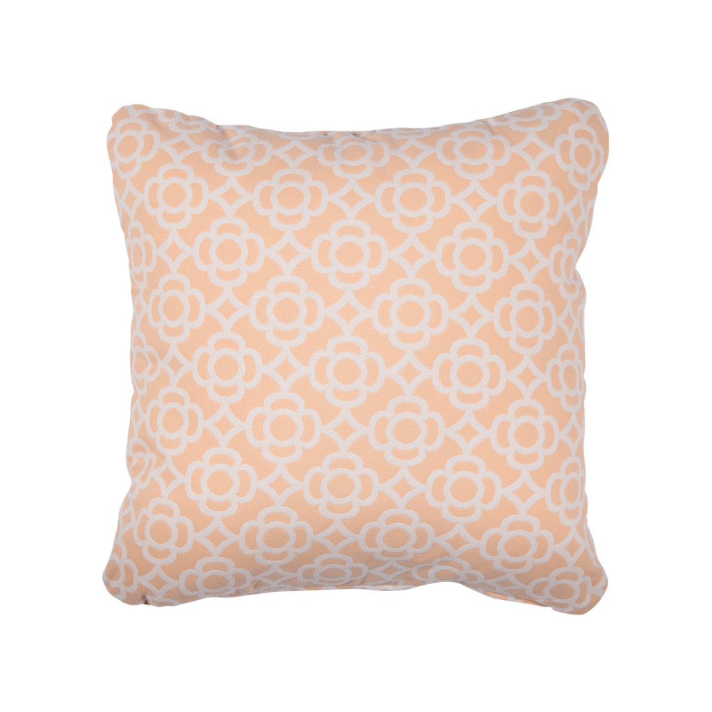 Un coussin rose blush avec un motif géométrique pêche et blanc.