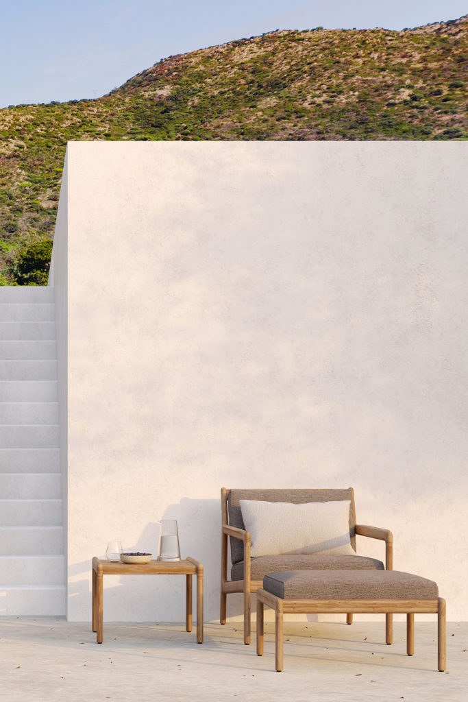 Un mur blanc avec une table d'appoint carrée Jack en teck et des chaises devant.