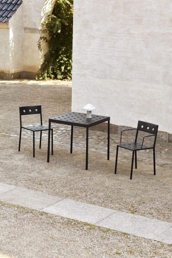 Une table et des chaises noires devant un immeuble.