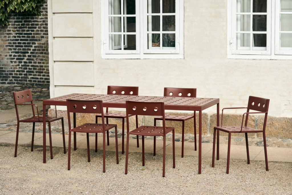Une table rouge balcon 190 cm et des chaises sur un balcon d'une maison.