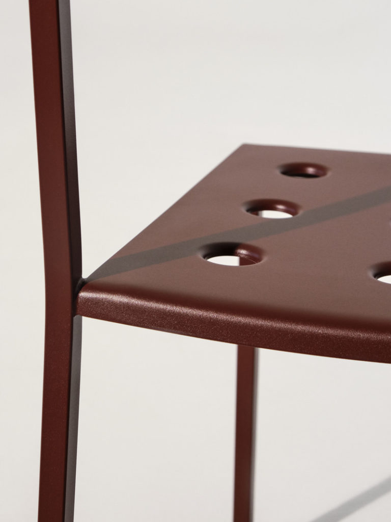 Une chaise en métal rouge avec des trous dans le dossier, parfaite pour les fauteuils Balcony.