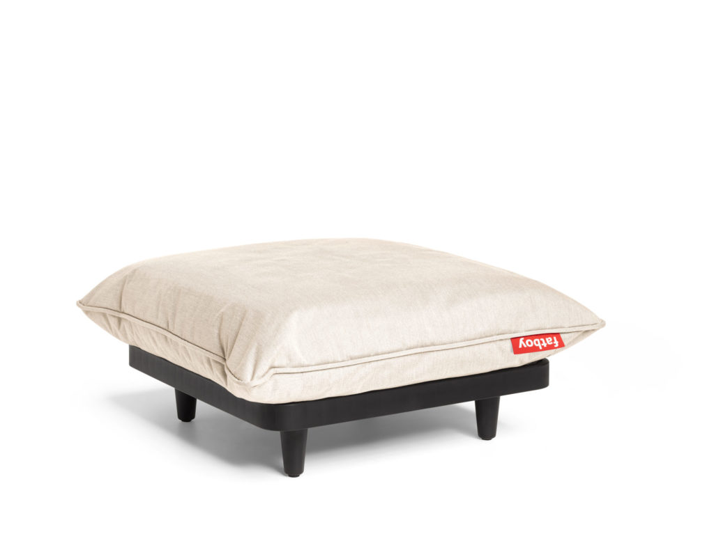 Un pouf beige avec un coussin sur le dessus.