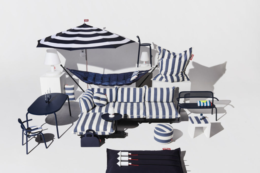 Un canapé, des chaises et un parasol à rayures bleues et blanches.