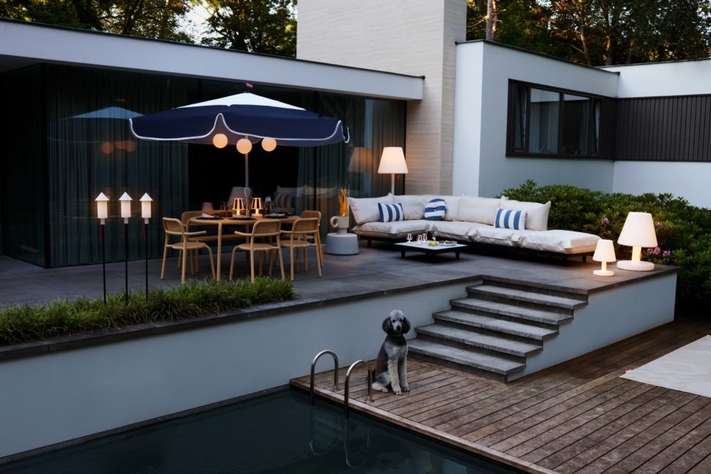 Un patio avec mobilier de jardin et parasol bleu.
