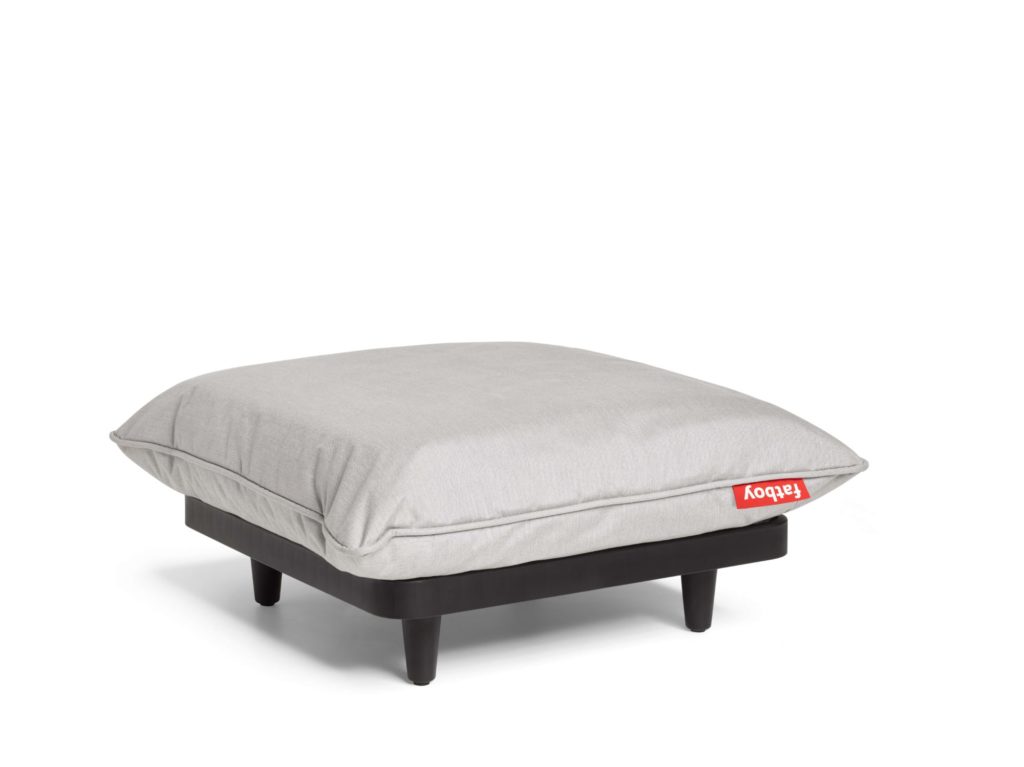 Un petit pouf gris avec un coussin sur le dessus, parfait pour un décor de salon de jardin.