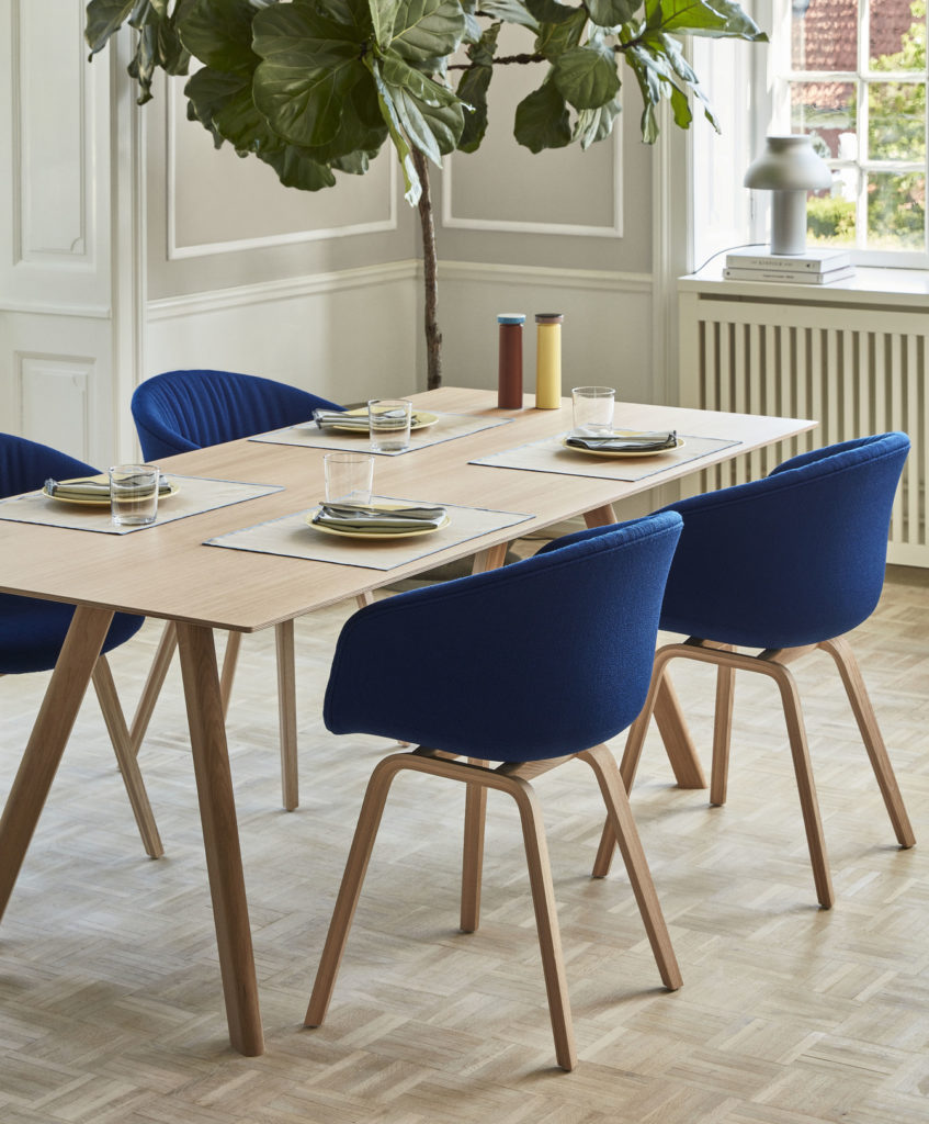 Une Table CPH 30 avec des chaises bleues et une plante.