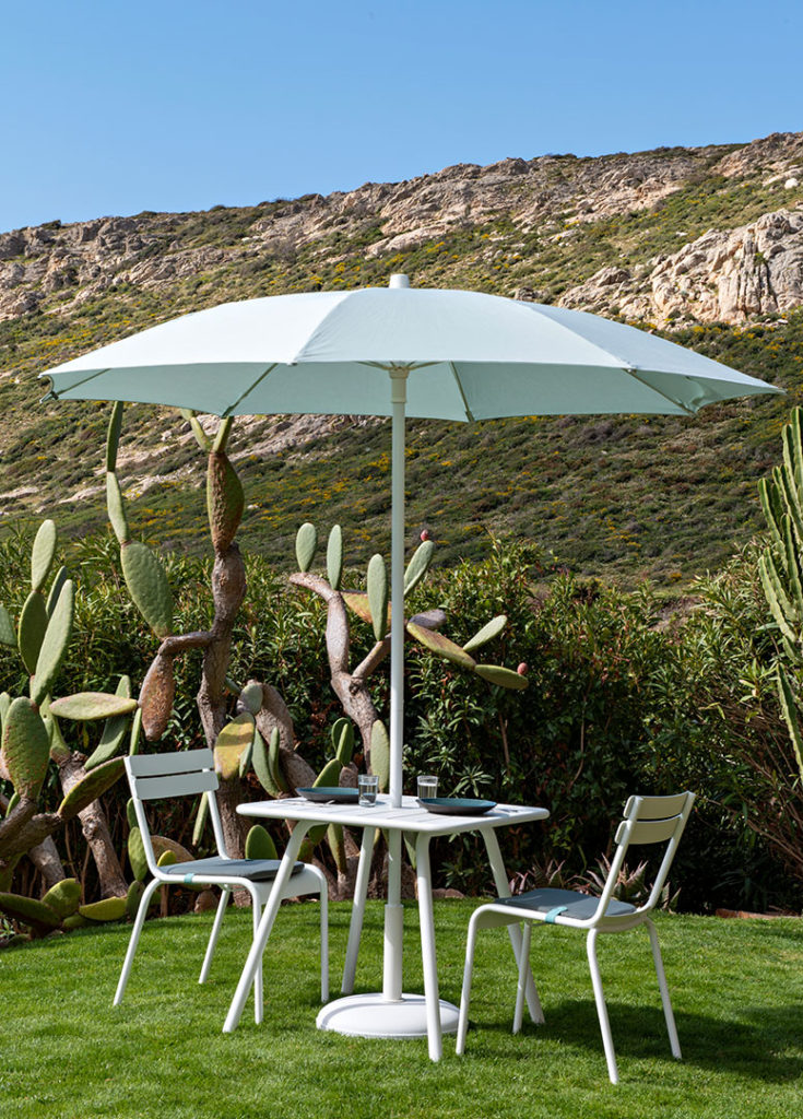 Parasol Luxembourg installé dans sa table avec un décor montagneux et ensoleillé