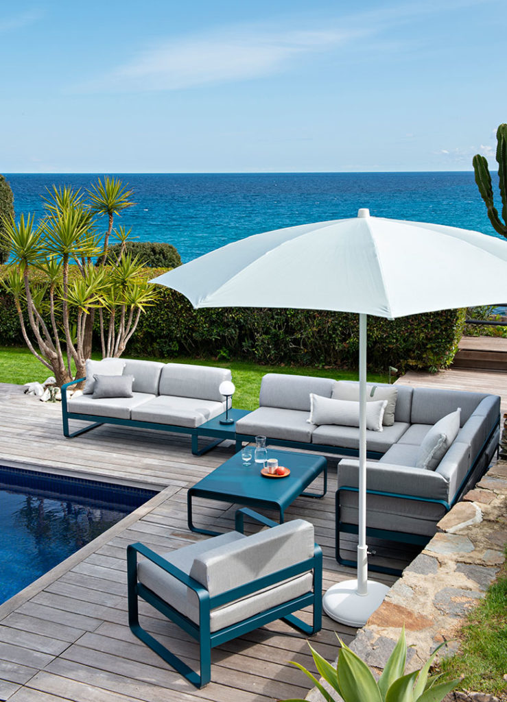 Une terrasse en bois au bord d'une piscine, ombragée par un Parasol Shadoo.