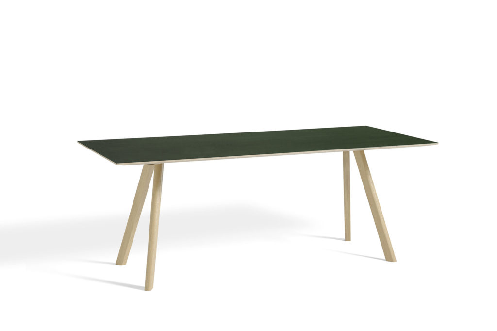 La table CPH 30 présente un plateau vert et des pieds en bois.