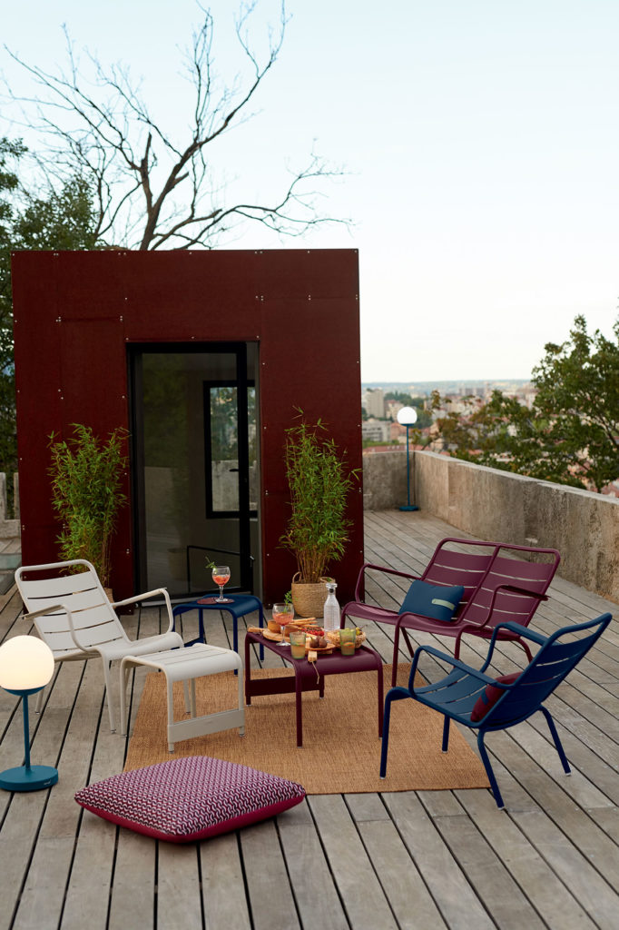 Une terrasse en bois colorée avec du mobilier Fermob 2022 dessus.
