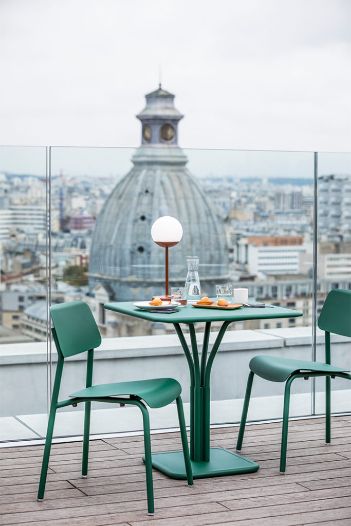 Deux chaises vertes sur un balcon Chaise Studie avec vue sur la ville.
