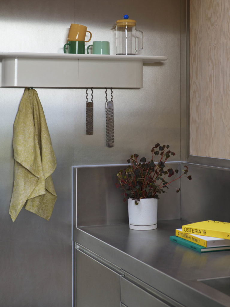 Etagère porte-manteau Korpus taille L en aluminium de la marque Hay dans une cuisine en métal avec une plante et des livres de cuisine