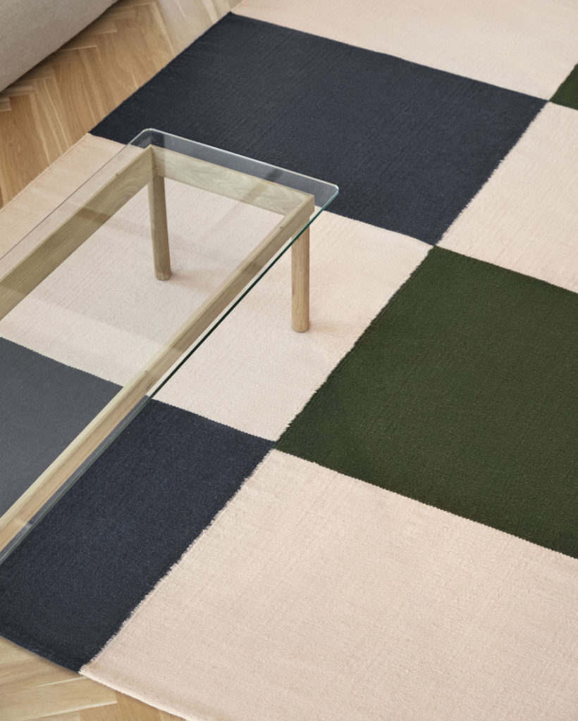 Tapis Ethan Cook en laine et coton de la marque Hay dans une pièce avec une table basse en verre et dans les tons verts, rouge, bleu, jaune , beige