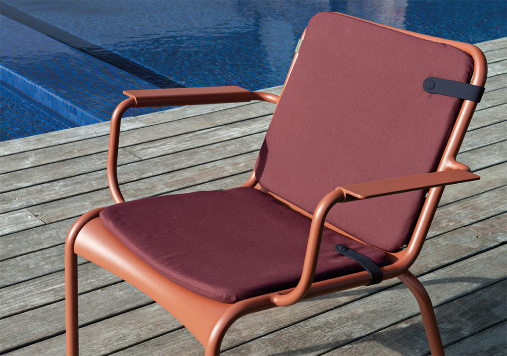 Une chaise Duo de galettes Color Mix 41 x 45 cm sur une terrasse en bois au bord d'une piscine.