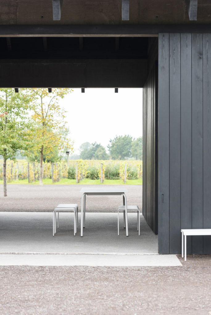 Une table August rectangulaire et des chaises dans une cour.
