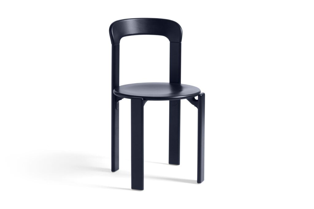 Une chaise longue bleu foncé et minimaliste avec un dossier incurvé et quatre pieds droits sur fond blanc.