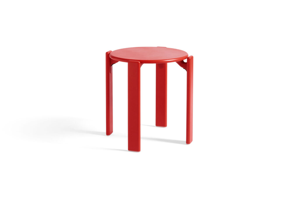 Le Tabouret Rey est un tabouret rouge écarlate à quatre pieds avec une assise ronde, joliment placé sur un fond blanc immaculé.