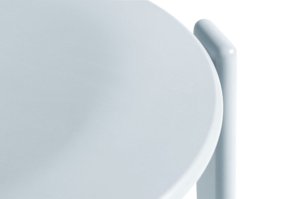 Gros plan d'un plateau de table rond gris clair avec une surface lisse, complété par un pied cylindrique rouge écarlate.