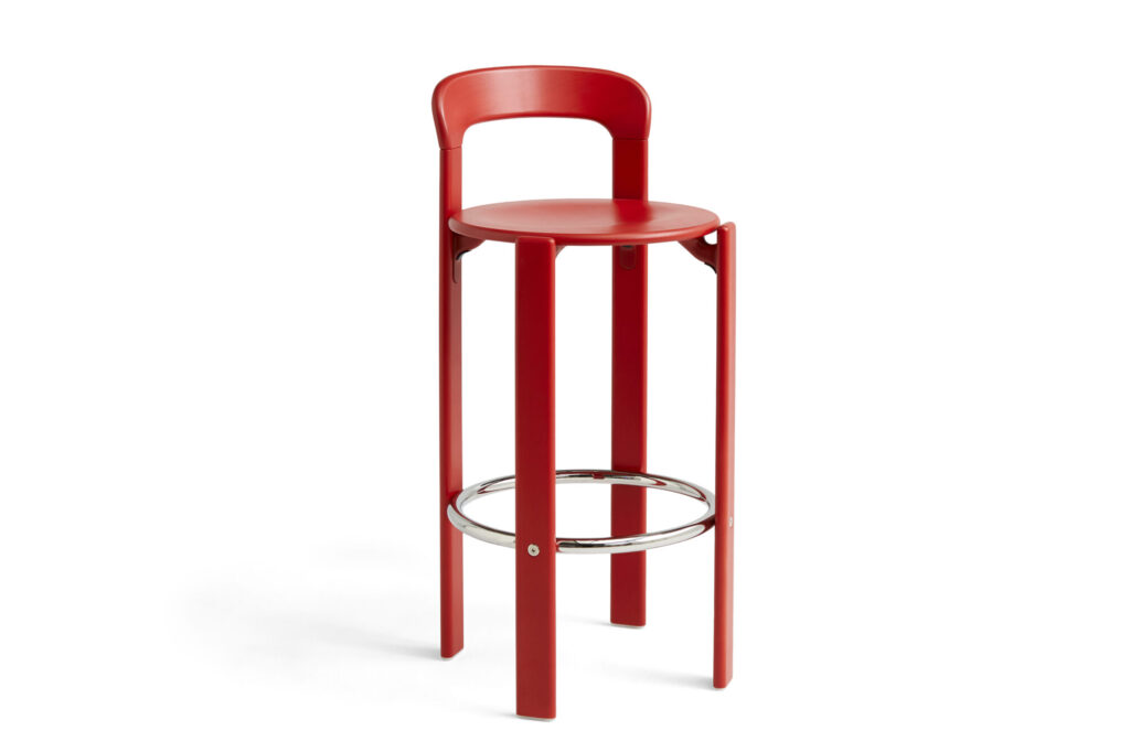 Tabouret haut rouge écarlate avec assise ronde, dossier et quatre pieds. Il est doté d'un repose-pieds circulaire en métal.