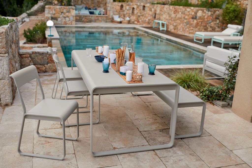 table Bellevie avec rangement central sur la largeur sur une terrasse de pierre au bord de l’eau