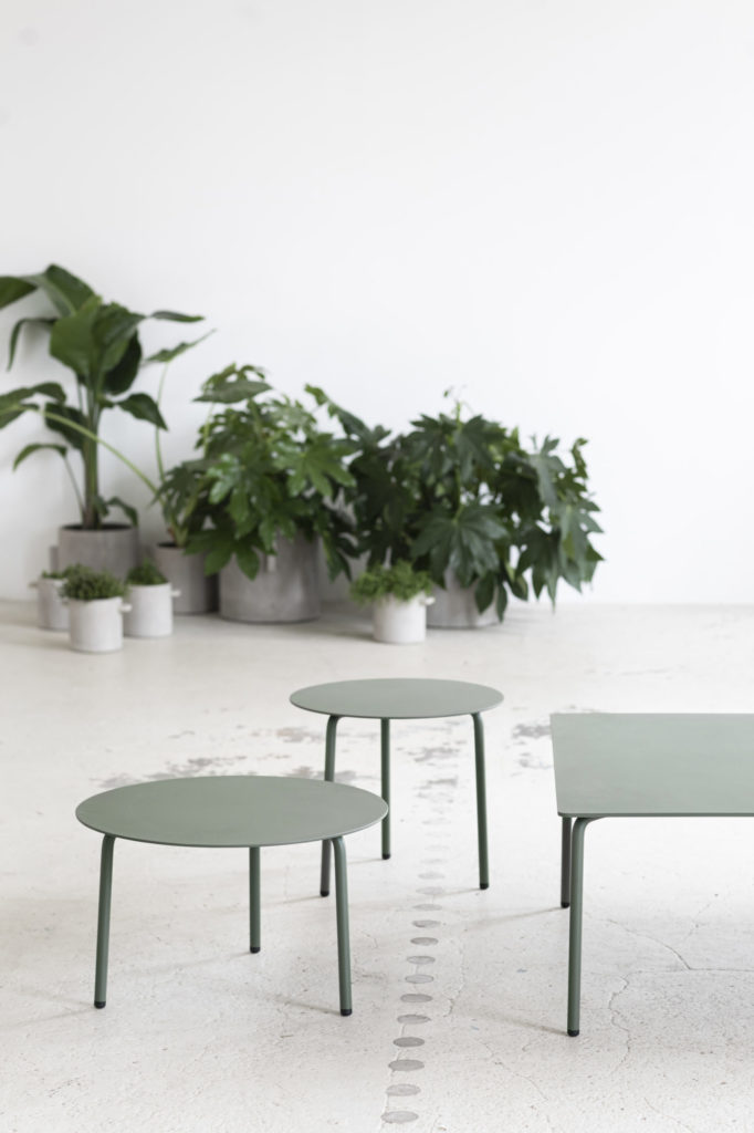 Trois Tables d'Août vertes rondes dans une salle avec plantes en pot.
