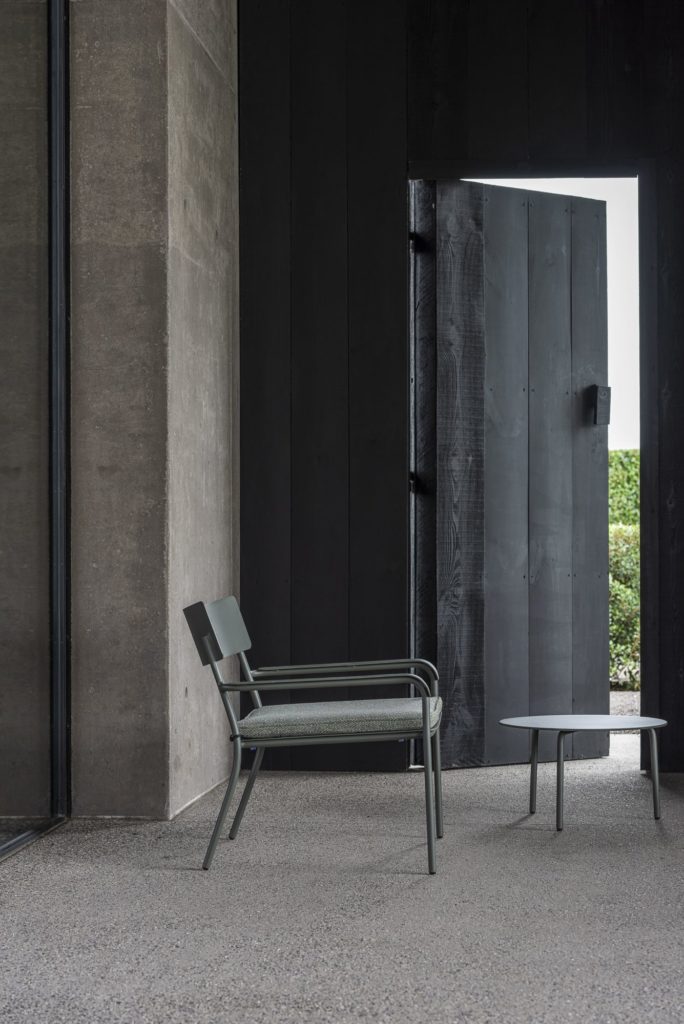 Une chaise noire et une Table de bar August devant une porte noire.