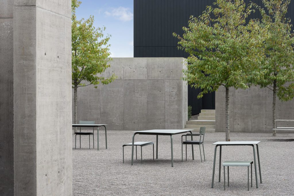 Un groupe de Table de bar August dans une cour bétonnée.