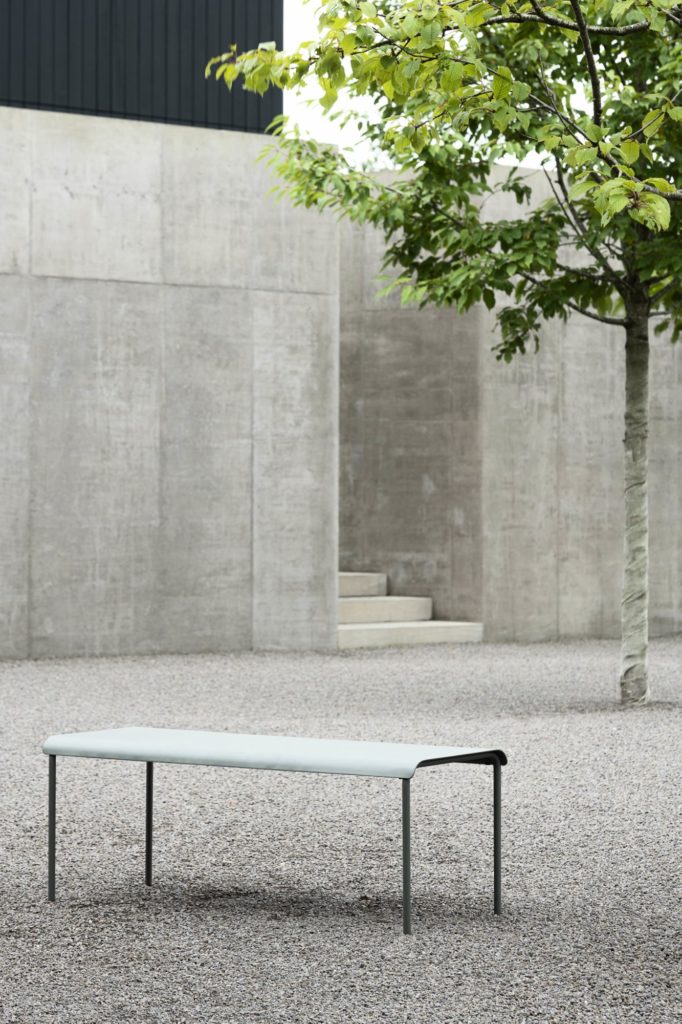 Un banc en béton Table de bar August devant un arbre.