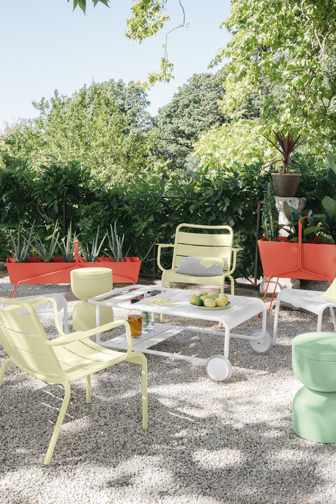Chaise avec accoudoir Luxembourg dans un jardin de gravier ensoleillé avec ensemble de tables basses