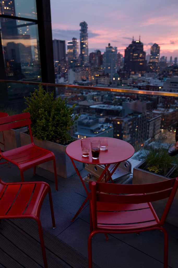 chaises d’extérieur fermob avec petite table sur une terrasse en plein New York au couché du soleil