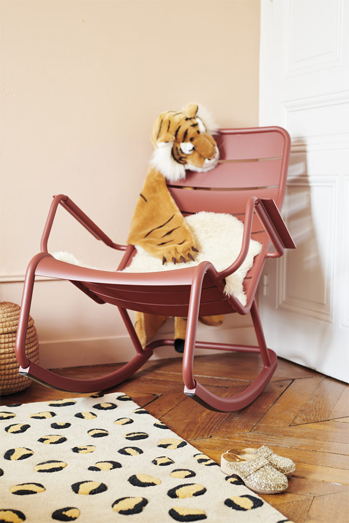 Rocking chair Luxembourg dans une chambre d’enfant avec un coussin en polaire blanc et peluche tigre