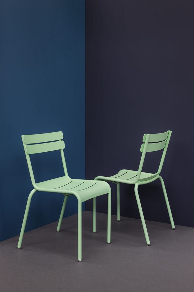 Deux chaises vertes contre un mur bleu.