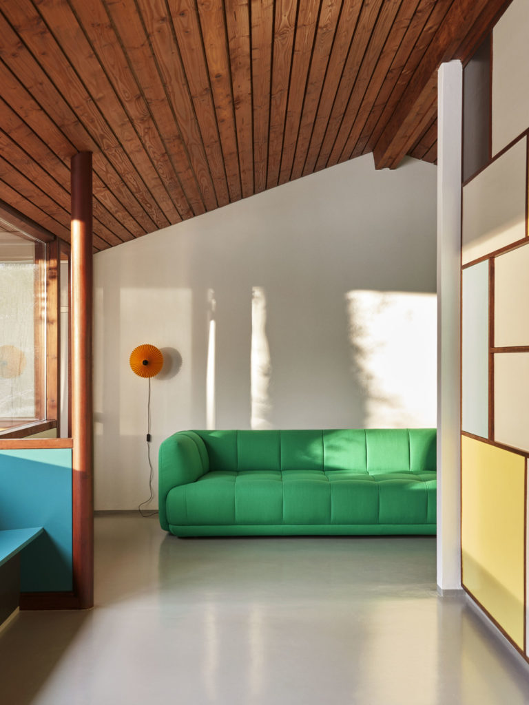 Canapé Quilton 3 places en tissu ou cuir de la marque HAY couleur vert dans une piece avec un toit en bois