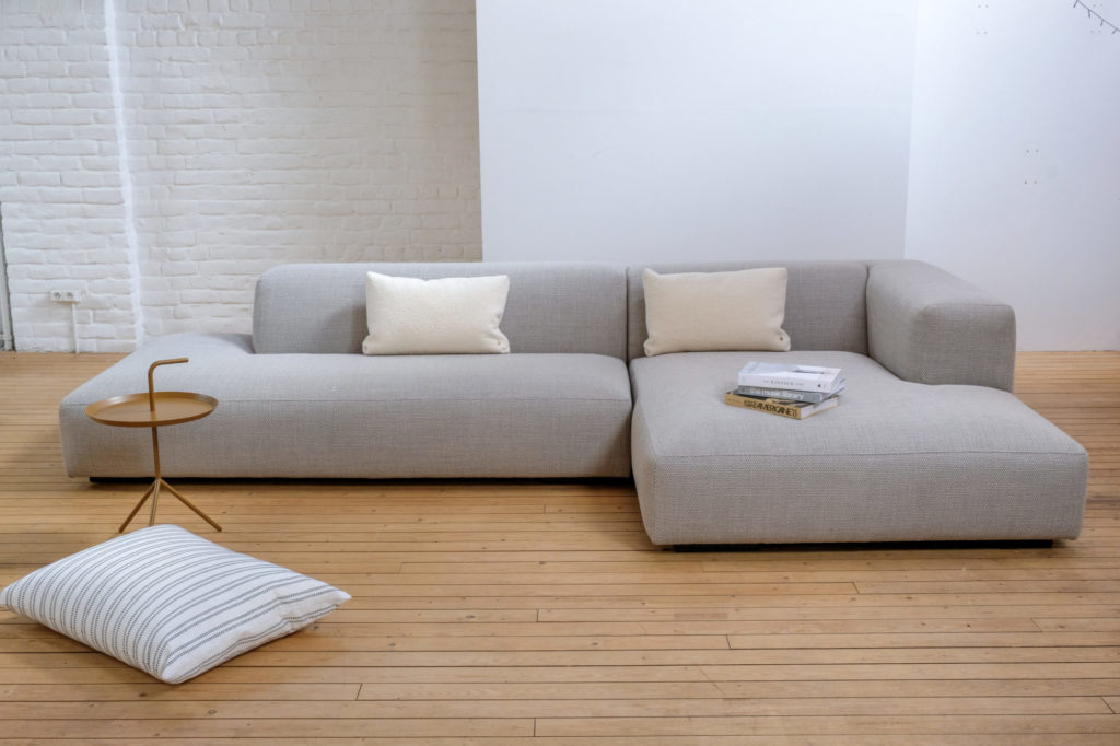 Un canapé sectionnel dans une pièce avec une table et des oreillers.
