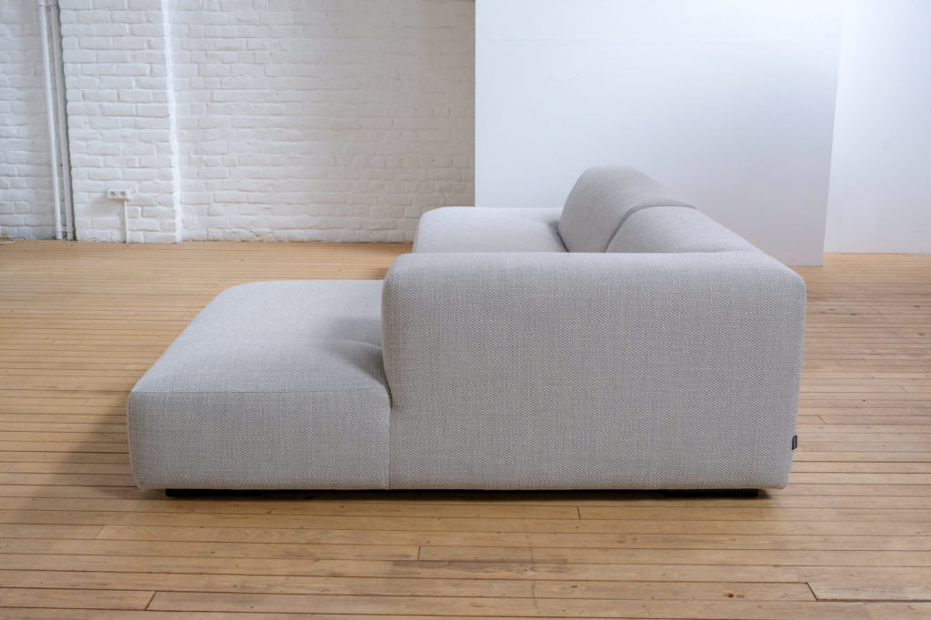 Un canapé blanc posé sur un parquet dans une pièce vide.